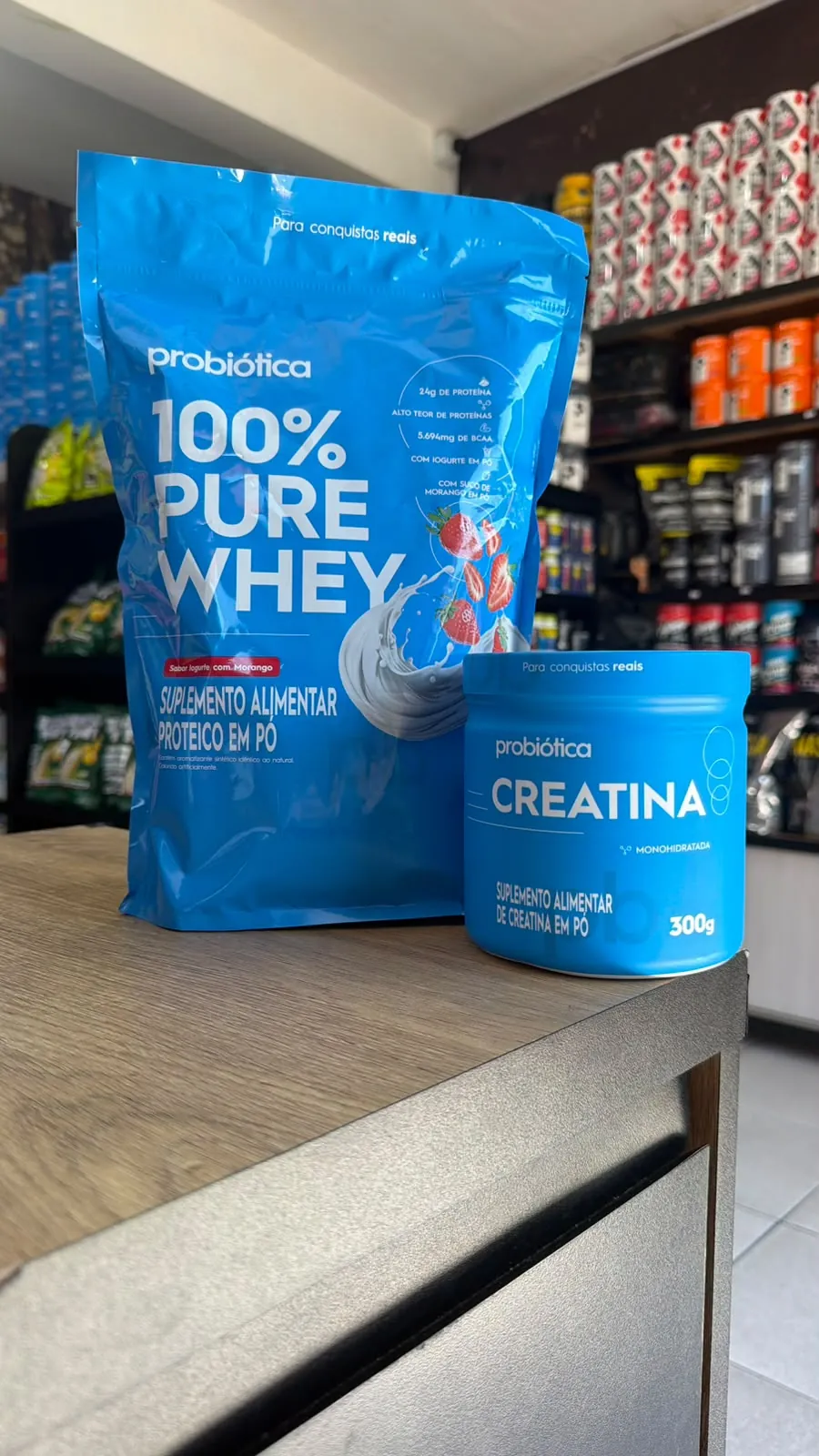 Pote de creatina monohidratada da Probiótica, 300 g, ao lado de uma embalagem de 100% Pure Whey